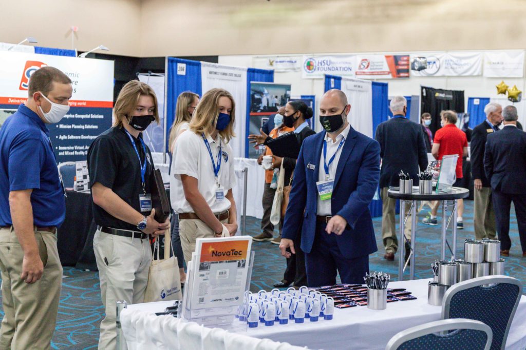 TeCMEN Booth with a Small Crowd Conference booth with display and visitors for TeCMEN Industry Day